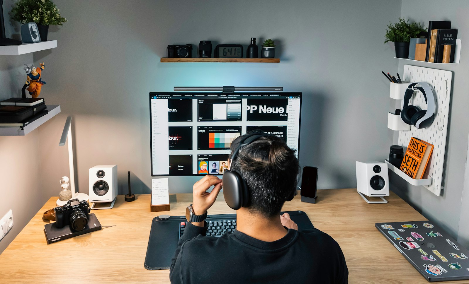 A person working at a neatly arranged desk with a monitor and headphones